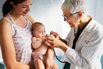 Pediatrician doctor medical examining little smiling baby, held by mother